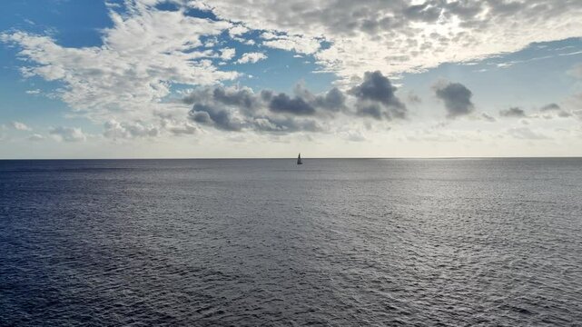 Drone shot of a little lonely sailboat out at sea daytime.