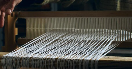 Super slow motion close up of female artisan skillfully working with woven weaving machine, using threads or yarns to craft cloth textile piece in her workshop studio at 1000 fps.  - Powered by Adobe