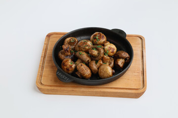 Fototapeta premium Grilled mushrooms with spices on a pan. Top view of brown champignon on pan on white background. Homemade food, healthy eating