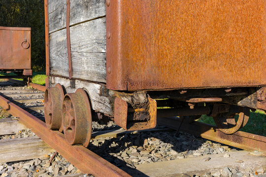 Rusty coal mine hutches or small wagons on narrow gauge rail tracks above ground