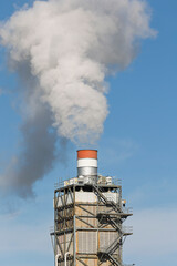 Industrial factory manufacturing plant chimney emitting steam and gas flue gases