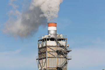 Industrial factory manufacturing plant chimney emitting steam and gas flue gases