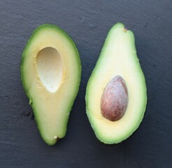avocado cut in half on a black stone background
