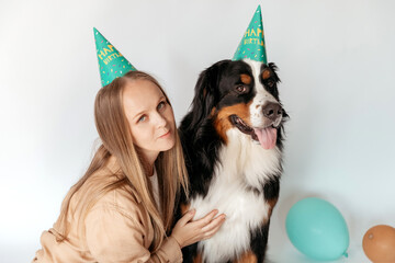 A blonde European woman with her beloved big dog in festive caps are sitting on a white background....