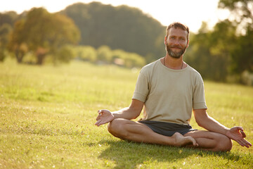 Fototapeta premium Meditation, lotus pose and portrait of man in nature for relax, calm and grounding exercise in morning. Health, peaceful and male person in padmasana for outdoor flexibility, balance and mindfulness.