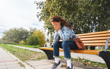Woman sits on the bench covers face with her hands and crying. Hopeless, mental illness,...