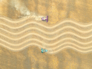 Aerial photo of two harvesters harvesting a field in a different manner