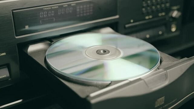 A tray with a compact disc comes out of a CD player in a hi-fi music center. Closeup. Macro. Shallow depth of field. Shot in motion