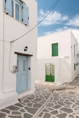 Charming Cycladic house with light blue shutters and doors in Paros, Greece, showcasing the simplicity and beauty of traditional Greek island architecture.