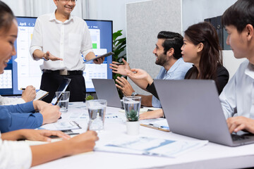 Project manager communicate and collaborate with team using project management software display on monitor, tracking progress of project task and making schedule plan at meeting table. Prudent