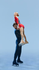 Graceful male and female figure skating pair executing dynamic lift on ice against cold blue...