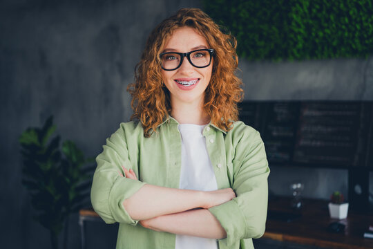 Photo of confident positive lady programmer dressed shirt glasses arms crossed indoors workplace workstation loft