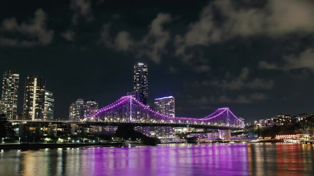 Timelapse nocturno del Story Bridge iluminado en morado, con luces desenfocadas de ferris y coches, Brisbane, Australia