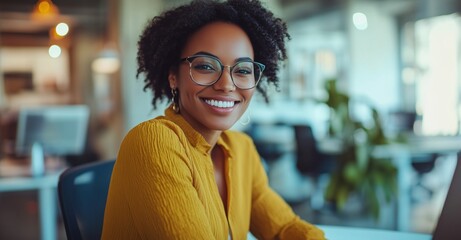 A woman wearing glasses and a yellow shirt is smiling at the camera