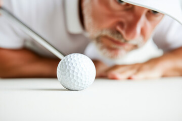 Focused golfer preparing to putt golf ball on green, showcasing concentration and precision in game. scene captures essence of golf with close up view