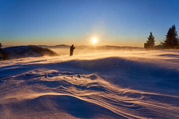 Bright sun over mountain range on cold winter day. Traveler in the wilderness, selective focus