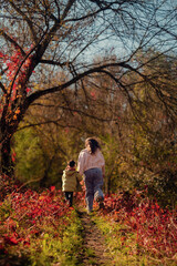 A mother and son run through the forest, enjoying quality weekend time together, playing outdoors in the countryside.