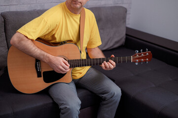 Obraz premium Man paying a acoustic guitar in office. Male musician playing music instrument