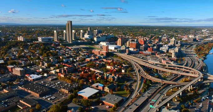 The Hudson River waterfront in the sunny scenery of Albany, New York, USA. Cars move quickly by the interchange in the city downtown. Aerial view.