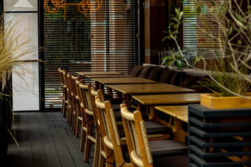 Stylish restaurant interior with wooden tables and chairs in a contemporary space during daylight.