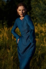 A model in a tight blue dress poses in nature