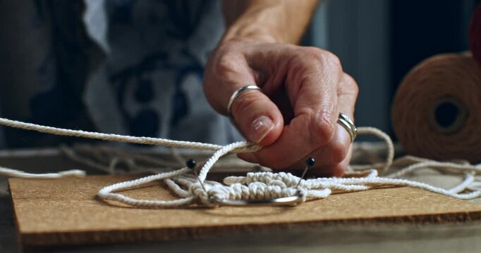 Super slow motion macro of artisan artist creates handmade and handicraft art piece with threads in creative workshop, capturing intricate beauty of craftsmanship and artistic expression at 1000 fps.