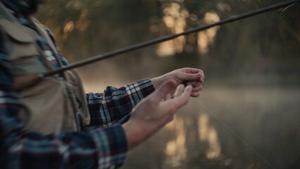 Young fly fisherman casting on a foggy river at sunrise
