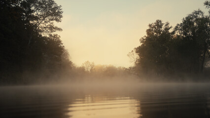 Fog drifting over a river during an autumn sunrise