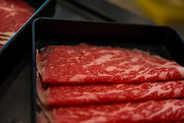 Close up of premium fresh sliced meat beef prepared for cooking in a shabu-shabu hot pot or sukiyaki.