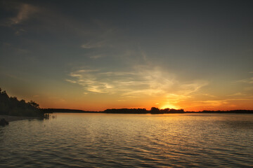 Golden sunset illuminating calm lake with cirrus clouds creating a serene atmosphere