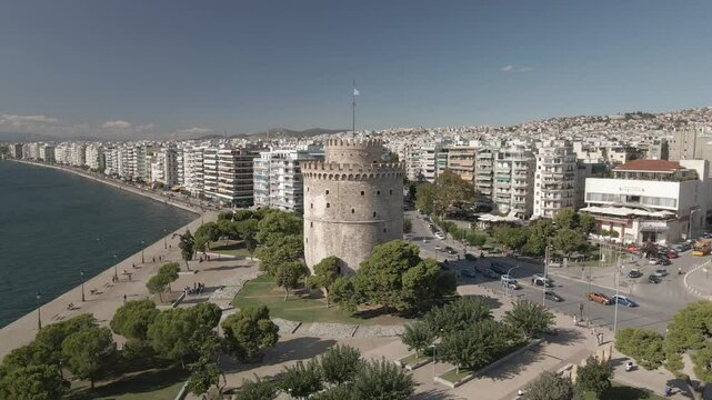 Thessaloniki, Greece The White Tower aerial. Circling the city landmark before the Thermaic Gulf waterfront, around buildings and traffic at Nikis Avenue.