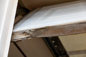 Overhead garage door weather stripping seal torn and broken. Home weatherproofing, repair and rodent prevention concept.