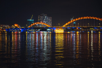 Naklejka premium Panorama of Dragon Bridge or Cau Rong Bridge over the Han River in Da Nang in Vietnam at night with a golden backlight