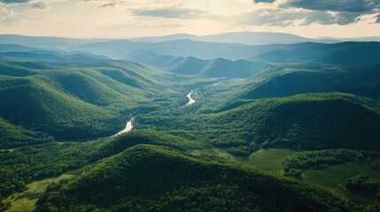 Obraz premium Aerial view of rolling mountains covered in rich green vegetation, valleys below dotted with rivers.