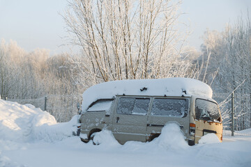 Snow covered abandoned old van in snow in winter. Season specific