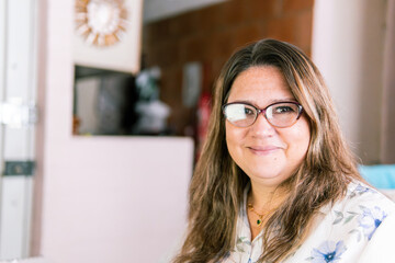 Plus-size Latina woman with glasses smiling confidently while working remotely in her home office