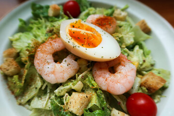 close up of salad with boiled egg, shrimp, cherry tomato and avocado cheese sauce on a white plate