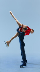 Figure skating couple performing impressive overhead lift against cold blue background. Strength...