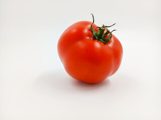 Red tomato with green branches and leaves. The vegetable from the farm. A fresh juicy product. Sauces, ketchup are made from it. Culinary theme, catalog, food packaging for a supermarket or blog.