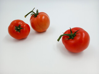 Red tomato with green branches and leaves. The vegetable from the farm. A fresh juicy product. Sauces, ketchup are made from it. Culinary theme, catalog, food packaging for a supermarket or blog.