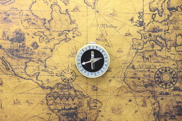 Classic round compass on background of old vintage map of world