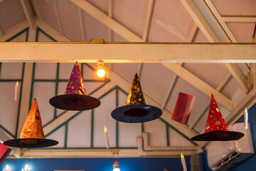 Halloween fancy witch  hats and candles hanging on ceiling inside cafe