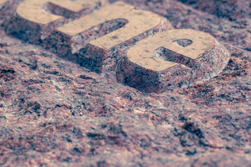 Naklejka premium raised relief engraved letters in gravestone made by stone carver. Rough granite stone monument fragment