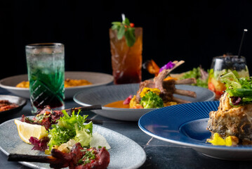 A beautiful table showcasing various dishes, including colorful salads, grilled meats, and elegant garnishes with stylish cocktails in unique glasses.