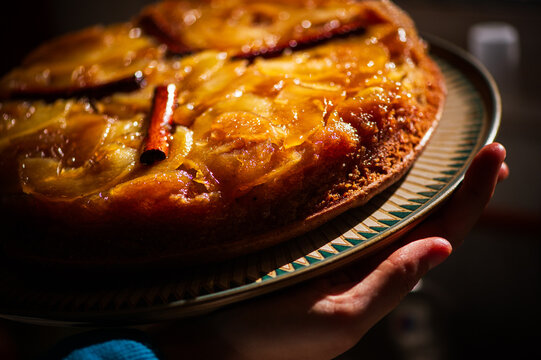 Closeup of a hand holding a cinnamon pie on a fancy patterned dish
