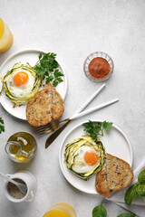 Two plates with fried eggs in zucchini noodle nests with sesame and juice in glass, healthy breakfast, top vertical view, copy space