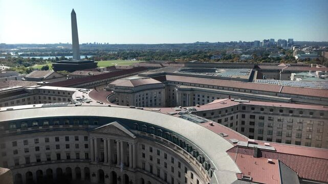 Aerial view of Washington DC, showcasing EPA curved building with multiple rooftops and a distant view of the Washington Monument, Potomac River.