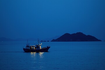 Obraz premium A boat is sailing in the ocean at night