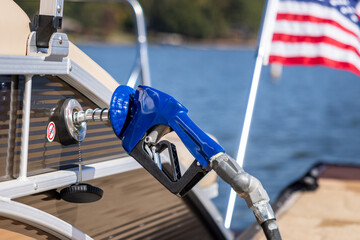 Boat refueling at marina. Gas pump nozzle filling pontoon party boat fuel tank.