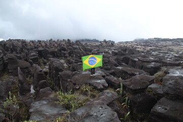 turista com bandeira do brasil em formações rochosas no alto do monte roraima, em trecho do lado brasileiro 